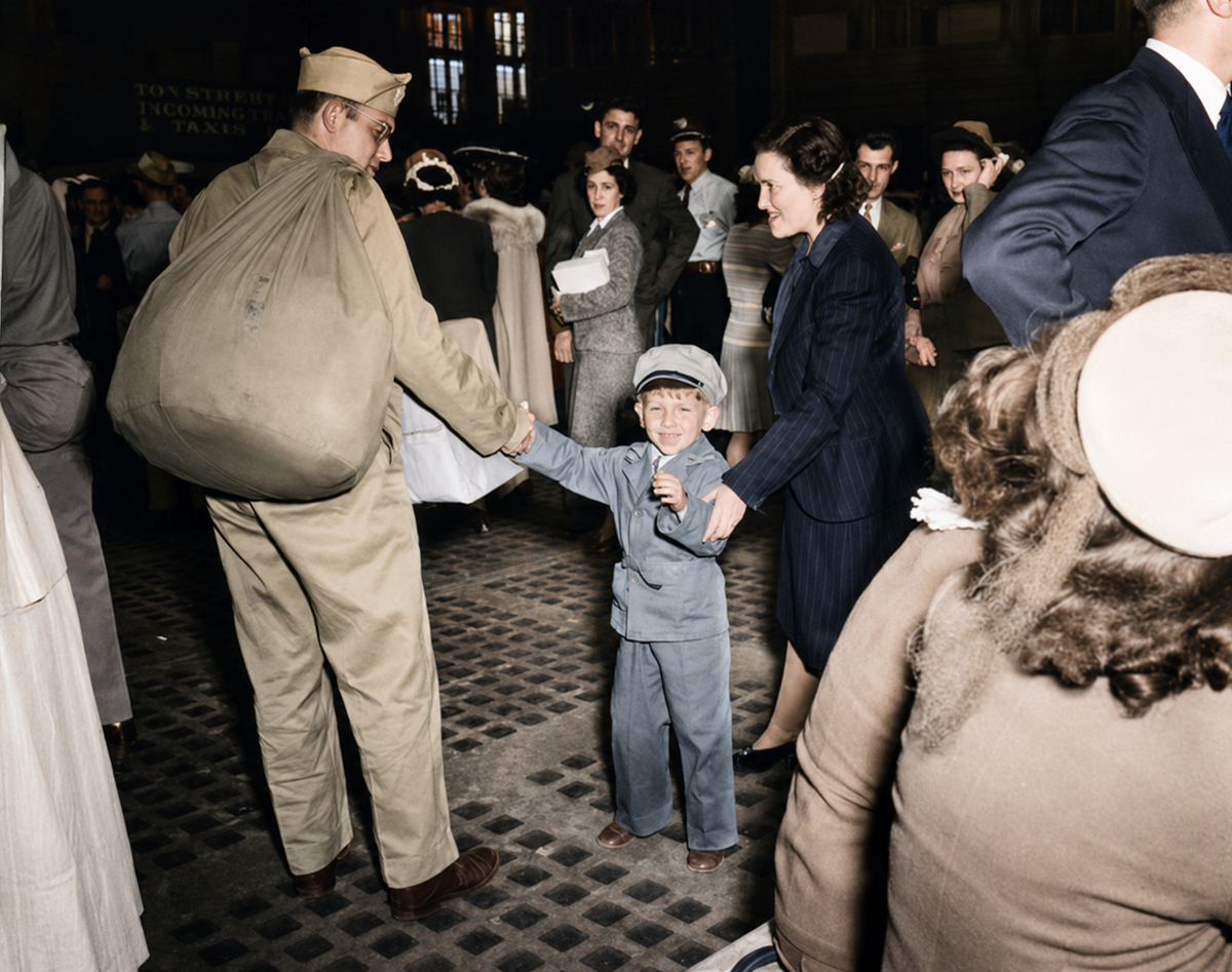 A soldier in uniform holds hands with a woman and a young boy, smiling, amid a crowd at a busy train station. The boy looks excited, and people around them are watching or waiting with luggage.