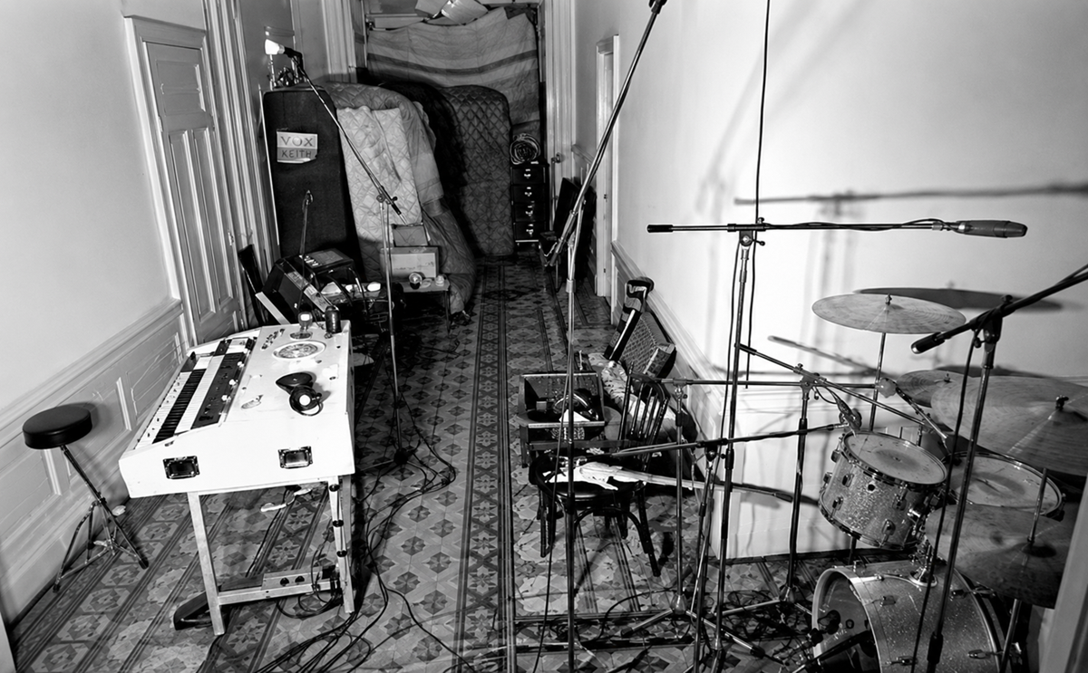 Black and white photo of a narrow recording studio with a tape machine, several microphones on stands, a drum set, and soundproofing blankets lining the back wall. The floor is tiled with a patterned design. 7. Deep Purple, Machine Head