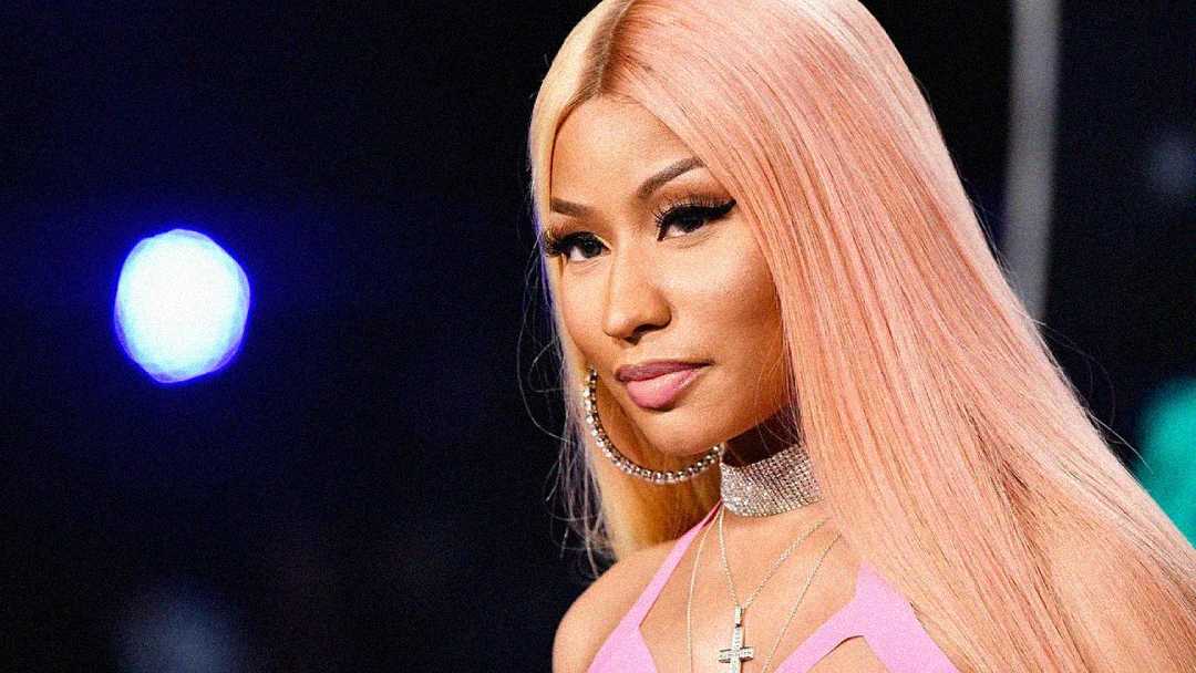 A woman with long, straight pink hair wears a sparkly choker, large hoop earrings, and a light pink top. She is facing forward with a calm expression. The background is dark with a bright blue light.