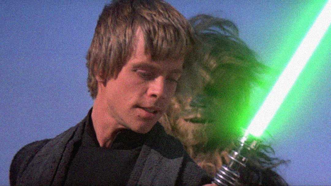 A man holding a green lightsaber stands in front of a tall, furry creature with a blue sky in the background.