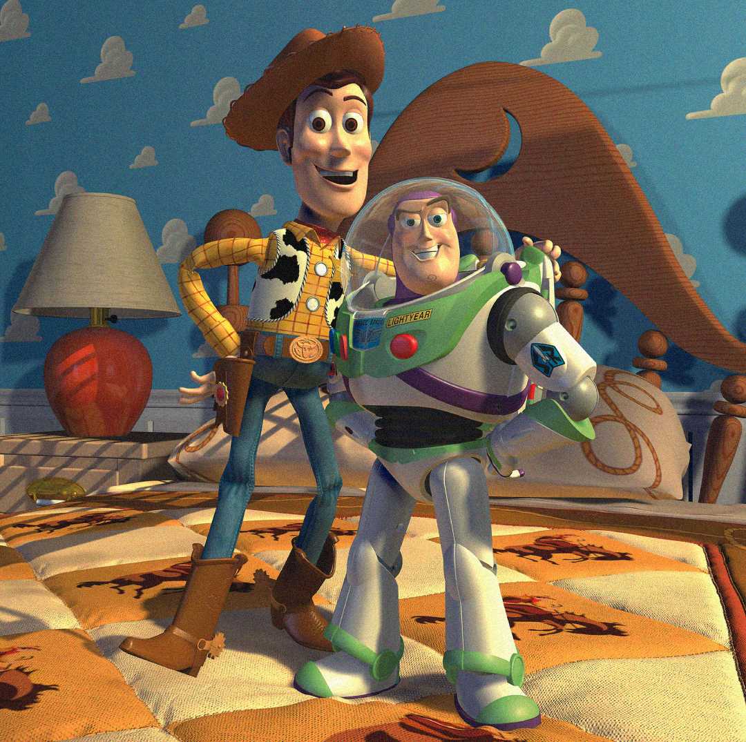 Woody, a cowboy doll, and Buzz Lightyear, a space ranger toy, stand together on a bed in a child's room with a cloud-patterned blue wall and a cowboy-themed bedspread.
