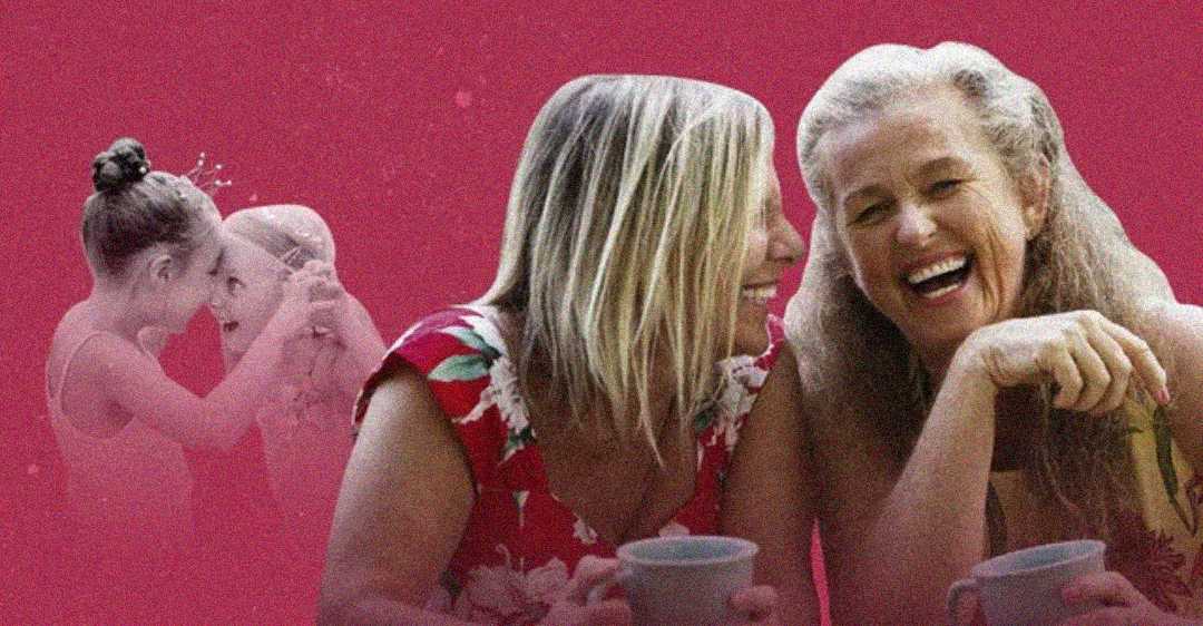 Two older women smiling and holding mugs sit together against a pink background. In the background, a faded image shows a young girl placing a crown on another woman’s head, symbolizing joyful moments across generations.