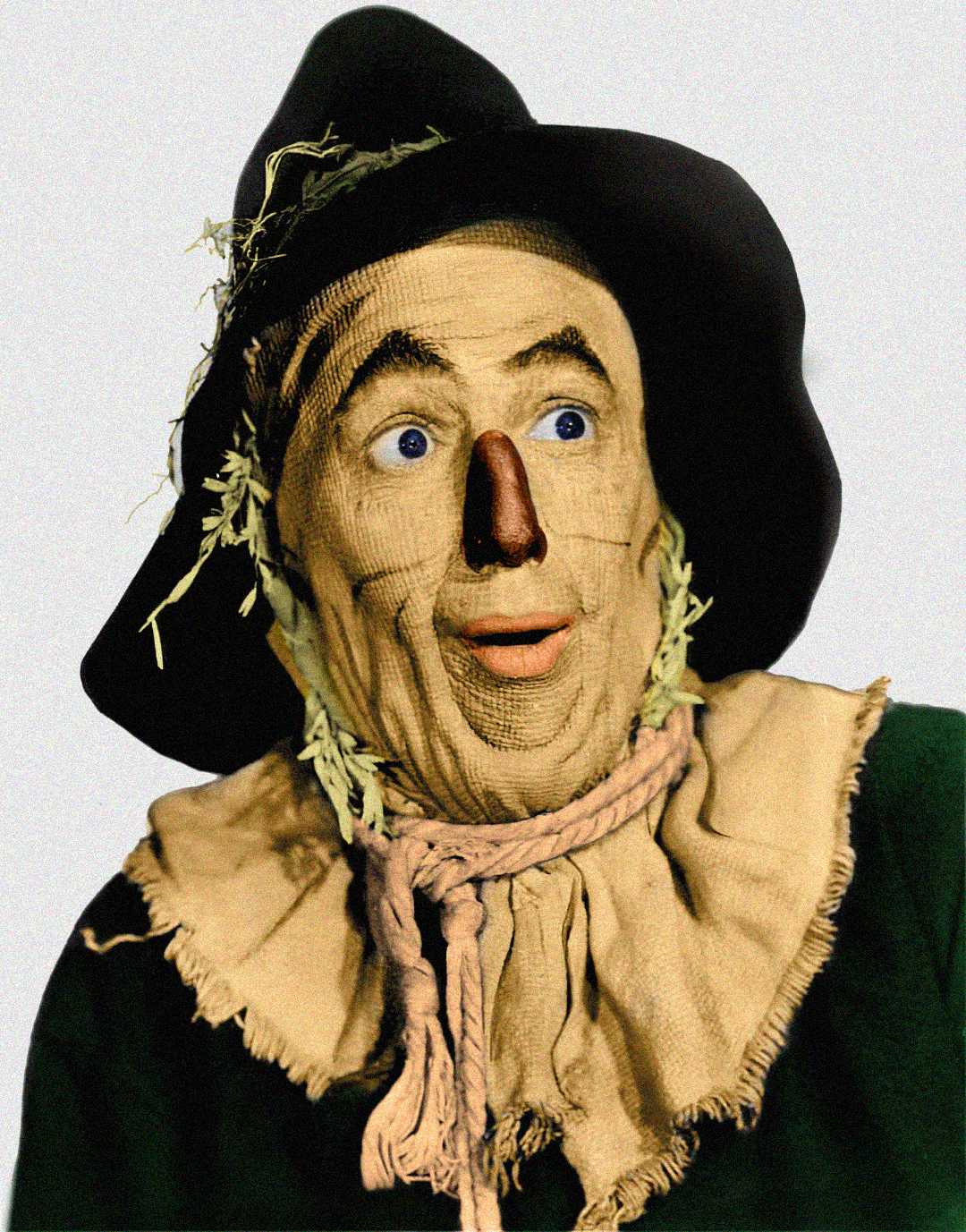 A person dressed as a scarecrow with a burlap face, straw sticking out, a wide-brimmed black hat, and a tan fabric collar, looking surprised with wide eyes and mouth slightly open.
