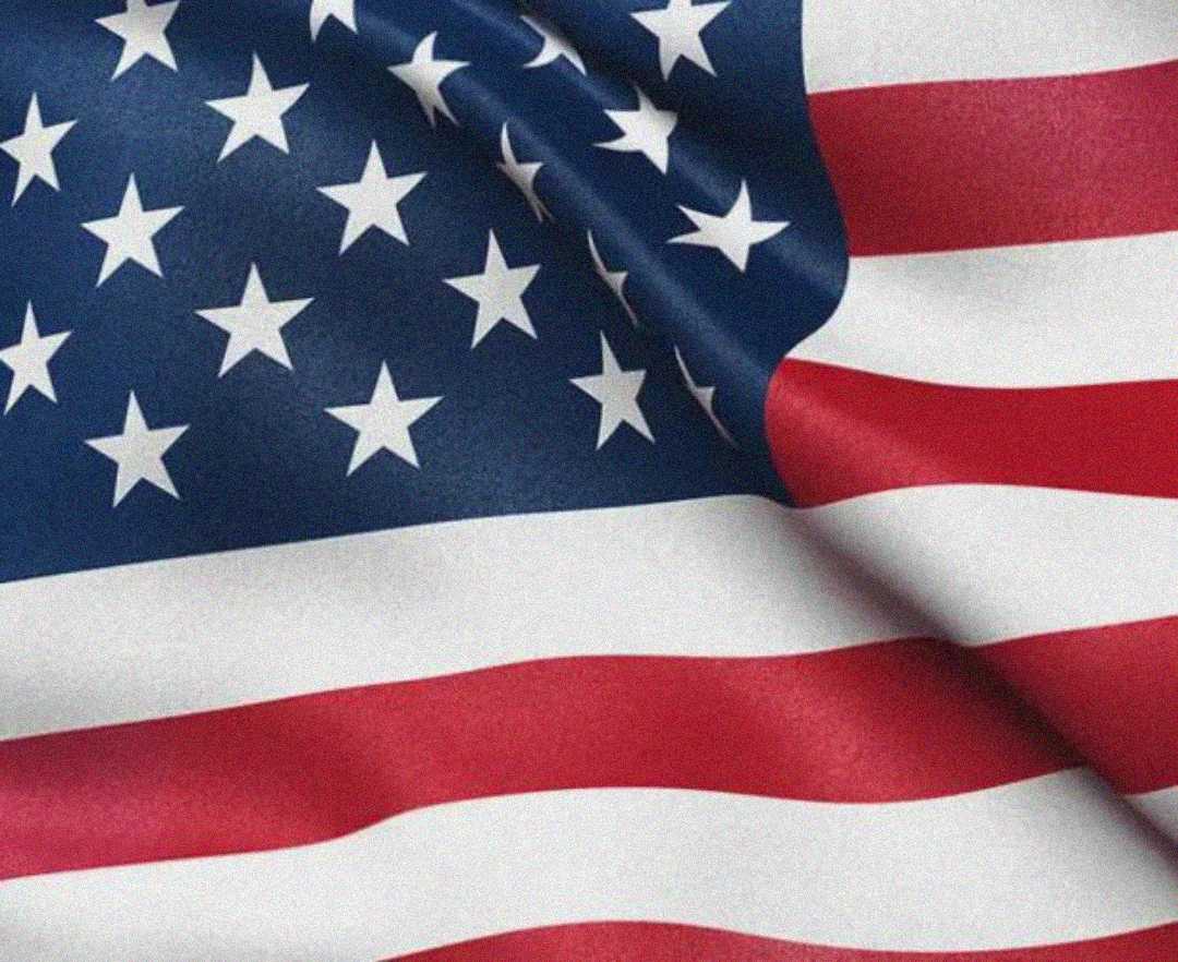 A close-up of the United States flag, showing red and white stripes and part of the blue field with white stars, slightly wrinkled as if gently waving.
