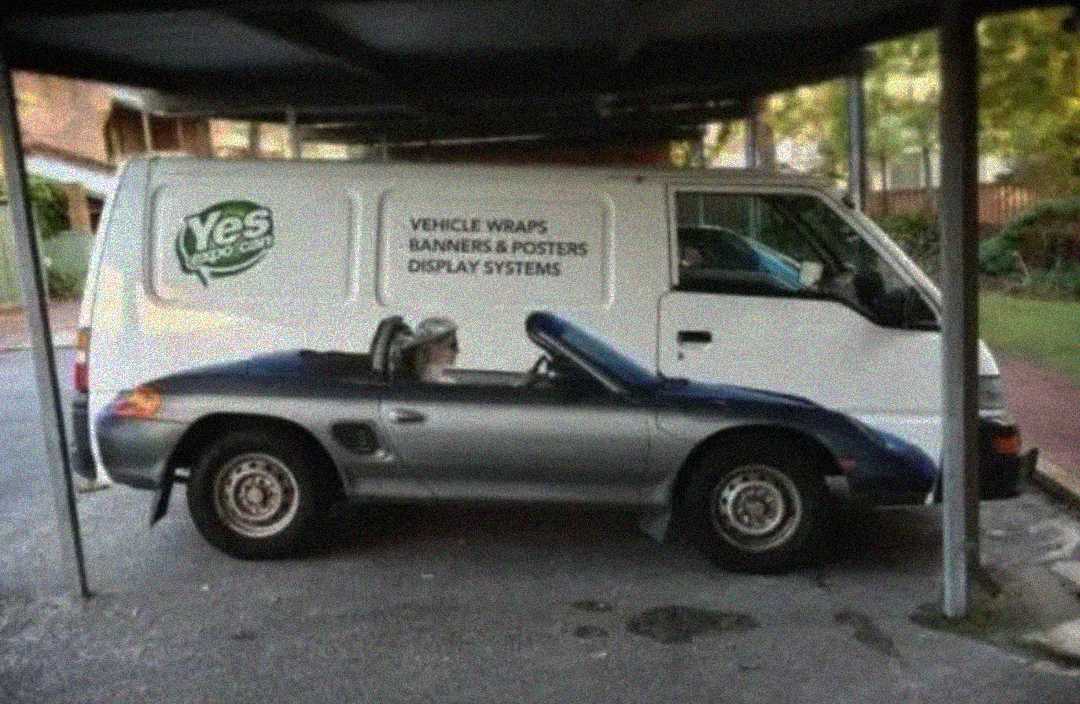 A van is parked next to a convertible car, and the design on the van's side aligns perfectly with the car, making it look like the van and car are merged into one vehicle.