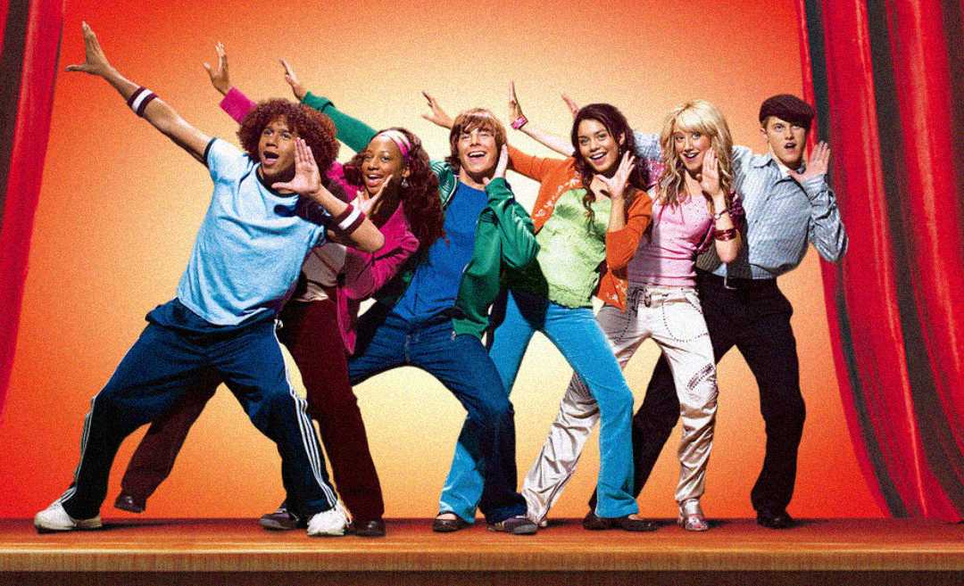 Six teenagers in colorful outfits pose energetically on stage with red curtains behind them, smiling and extending their arms in playful dance positions.