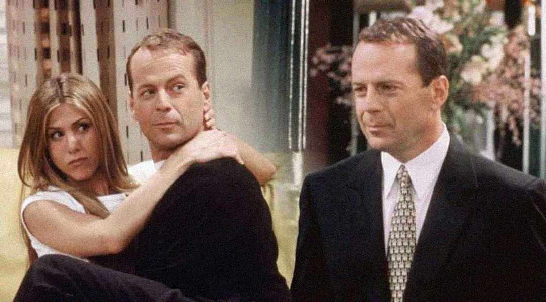 A man in a black shirt carries a surprised-looking woman in his arms, while another image of the same man in a suit and tie appears beside them. The background is indoors with floral decor.