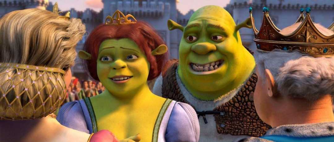 Two green ogres, Fiona and Shrek, stand smiling among a royal crowd wearing crowns and elaborate attire in a bright, medieval castle courtyard scene from the animated movie "Shrek.