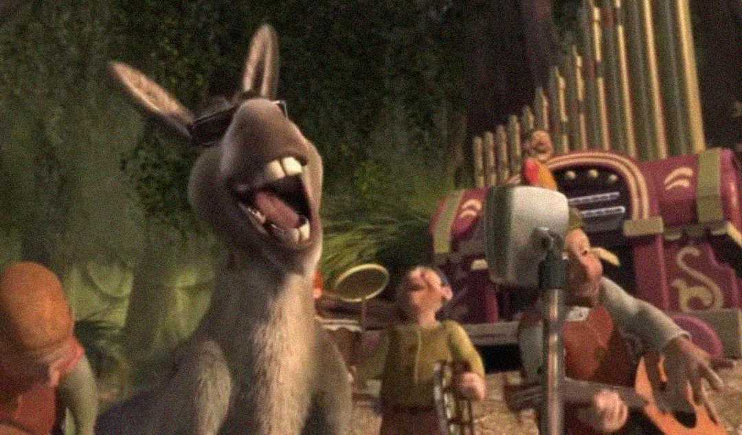 A gray donkey wearing sunglasses sings into a microphone with a wide open mouth, while several dwarfs play instruments and dance around him outdoors, with a large organ in the background.