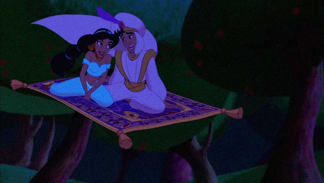 Animated scene of a young couple sitting together on a flying carpet, soaring above trees at night. The girl has long black hair and wears a blue outfit, while the boy wears a white outfit with a purple feathered turban.