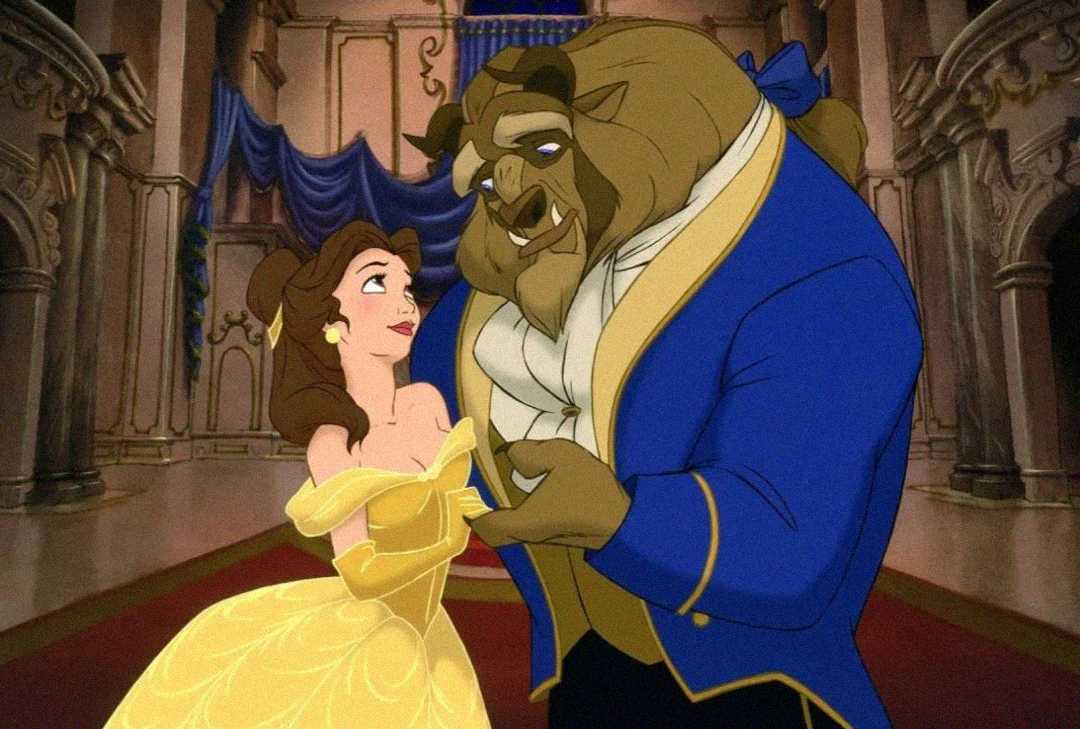 Animated scene of a woman in a yellow gown and a large beast in a blue coat dancing together in a grand, ornate ballroom with columns and draped blue curtains.