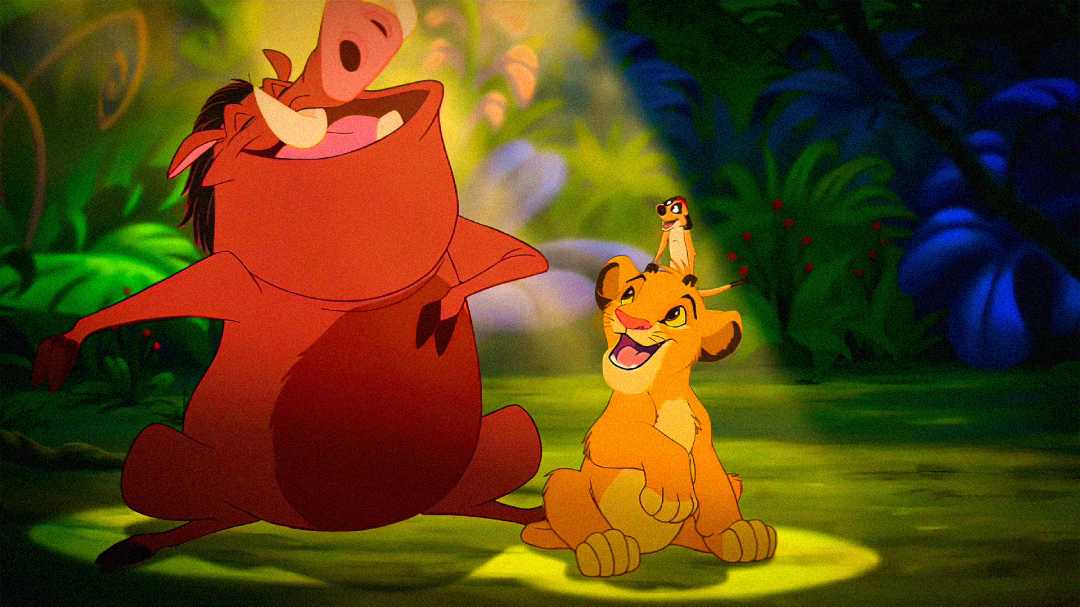 Animated scene from The Lion King showing Pumbaa the warthog, Simba the lion cub, and Timon the meerkat in a lush jungle, all smiling and bathed in warm sunlight.