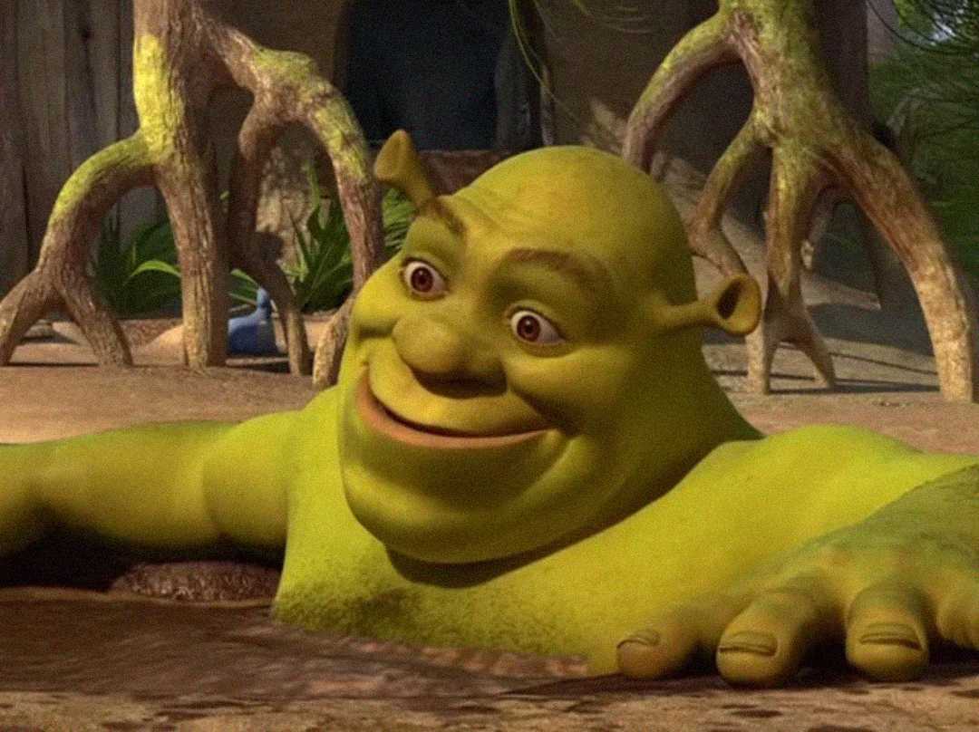 Shrek, a large green ogre with small ears, smiles while relaxing in a muddy swamp, his arm resting on the surface of the water and trees visible in the background.