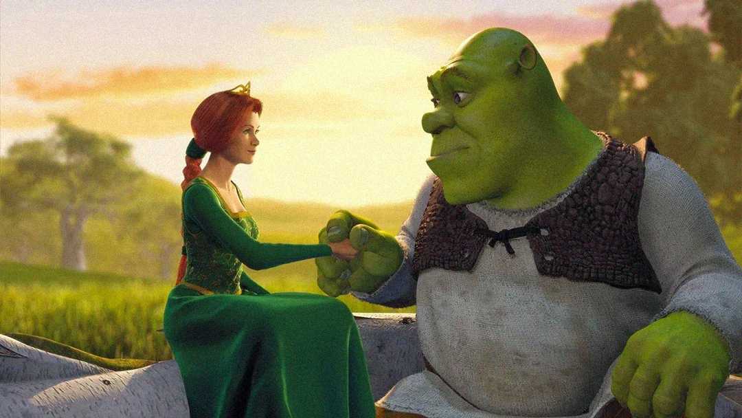 Princess Fiona, wearing a green dress and tiara, holds hands with Shrek, a large green ogre in a brown vest, as they sit together on a log in a sunlit, grassy outdoor setting.