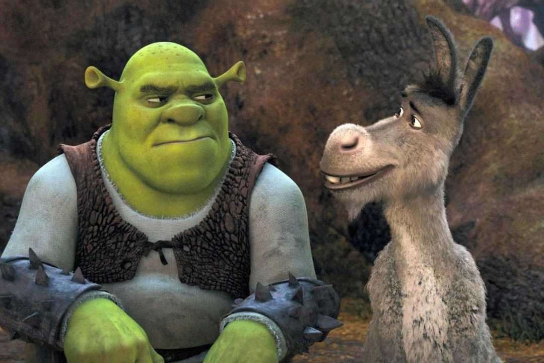 A green ogre and a gray donkey, both animated characters, sit side by side in a forest setting. The ogre looks skeptical while the donkey smiles, appearing to be in mid-conversation.