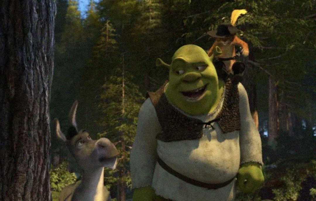 Shrek, an ogre, walks through a forest with Donkey by his side and Puss in Boots sitting on his shoulder. They appear to be talking and are surrounded by tall trees.