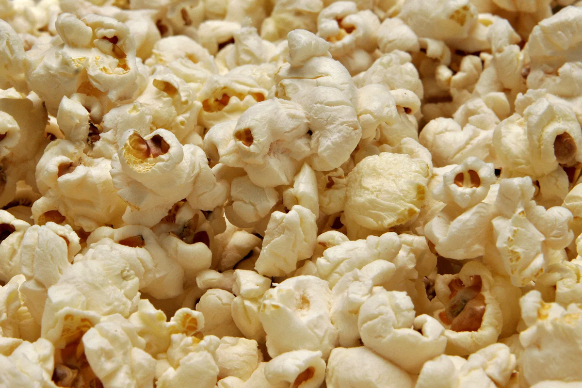A close-up view of a pile of freshly popped popcorn kernels, showing their fluffy, irregular shapes and light buttery color.
