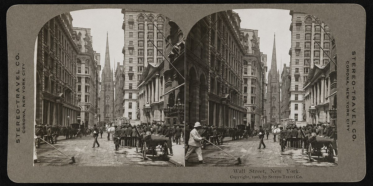 Black-and-white stereoscopic photo of Wall Street, New York City, circa 1905, showing busy street life with people, horse-drawn carts, and tall buildings lining both sides of the street.