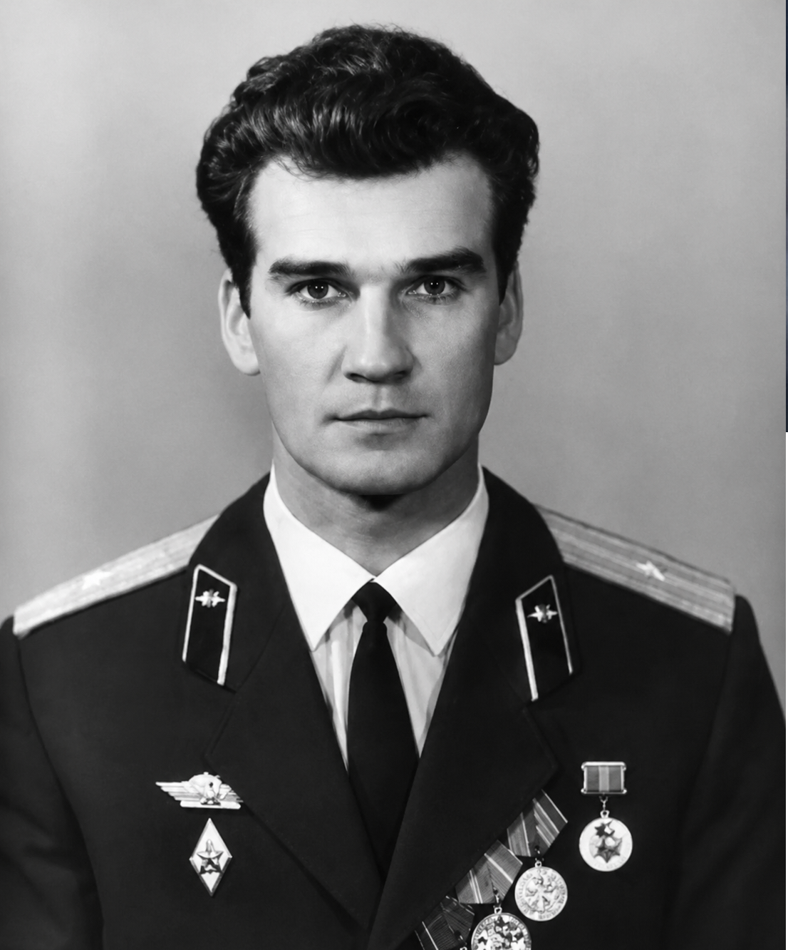A young man in a military uniform with shoulder epaulettes and several medals and pins on his chest, posing for a formal black-and-white portrait against a plain background.