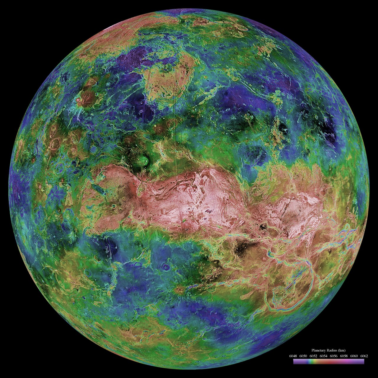 Colorful, detailed false-color map of Venus showing its surface topography, with greens, blues, and pinks highlighting different elevations and geological features, set against a black background.