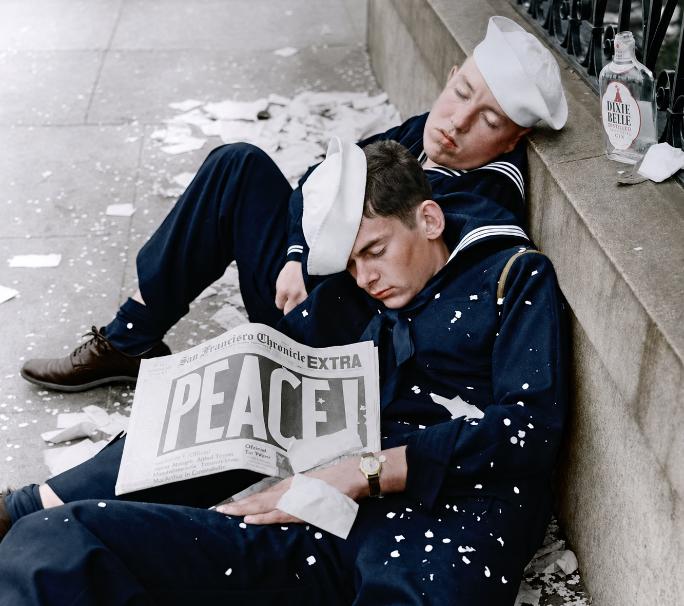Two sailors in navy uniforms are sleeping on a city sidewalk, surrounded by confetti. One holds a newspaper with the bold headline "PEACE!" A glass bottle is on the steps beside them.