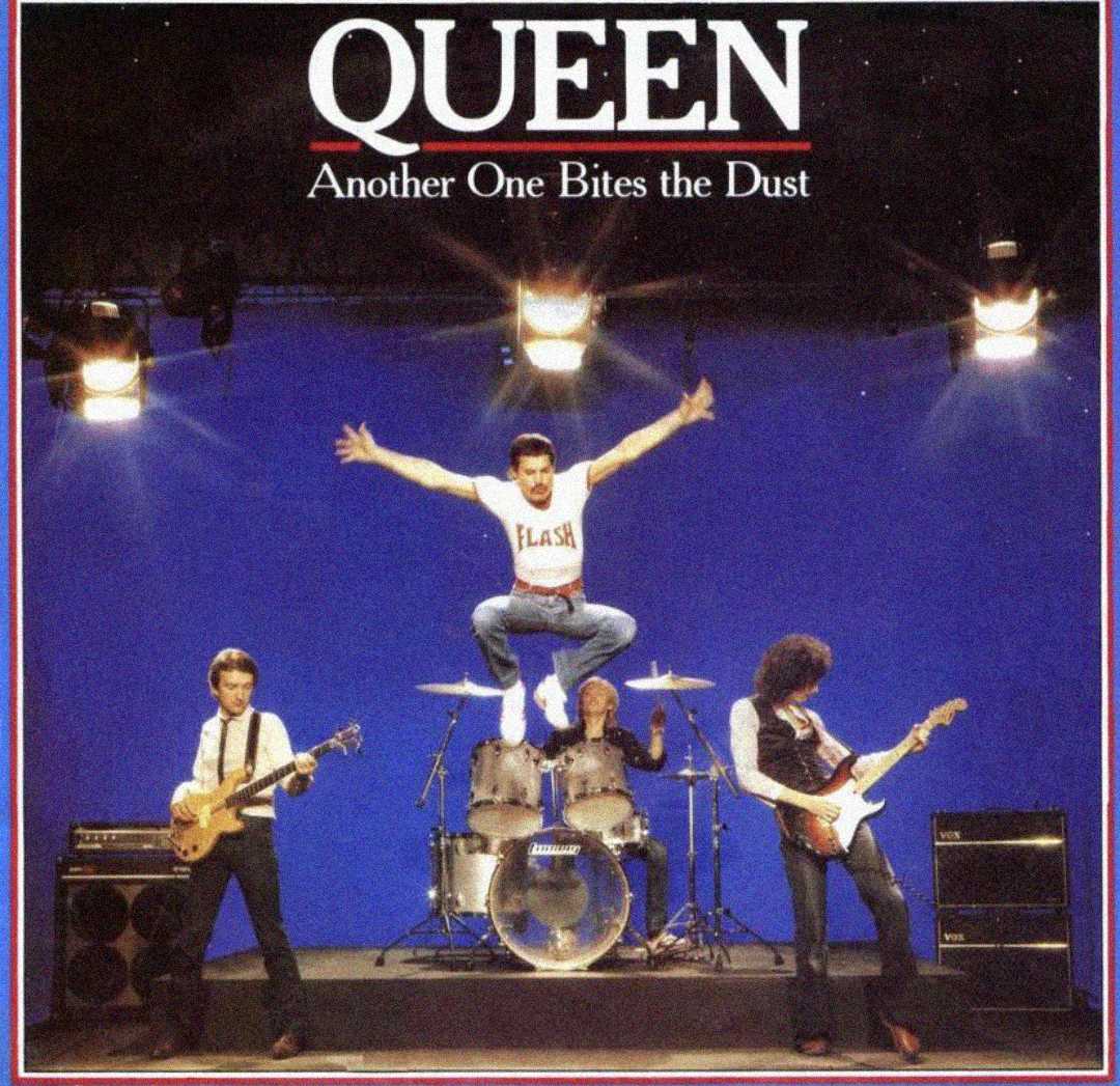 Four band members of Queen perform on stage with a blue background; the singer is mid-air in a jump with arms outstretched, while the others play guitar, bass, and drums. Text above reads "QUEEN Another One Bites the Dust.