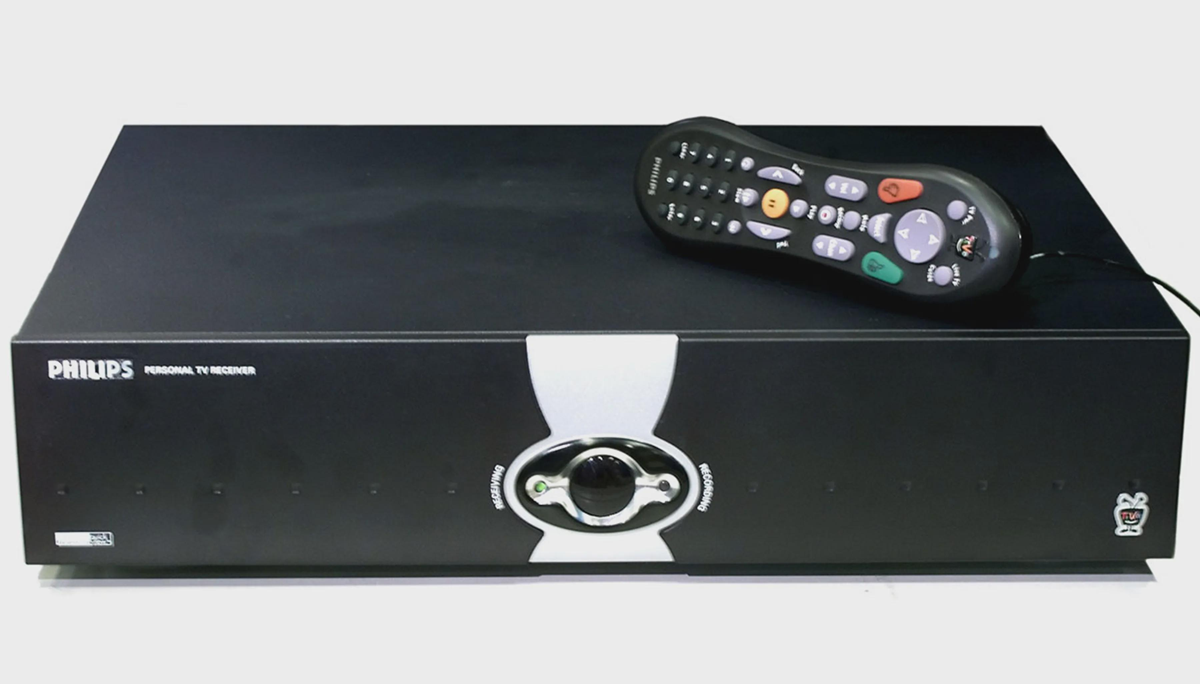 A black Philips personal TV receiver with a central dial and indicator lights on the front, shown with a black remote control resting on top.
