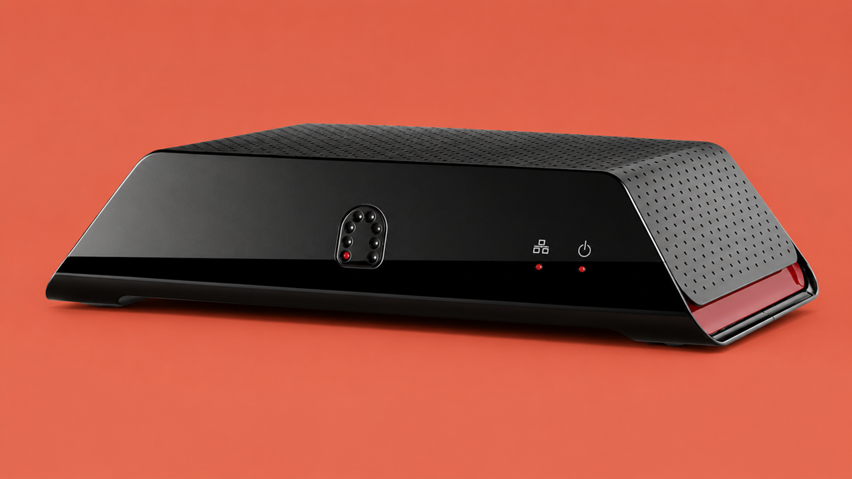 A black electronic device with a vented top and sloped sides, featuring indicator lights and a power button on the front, is shown against an orange background.