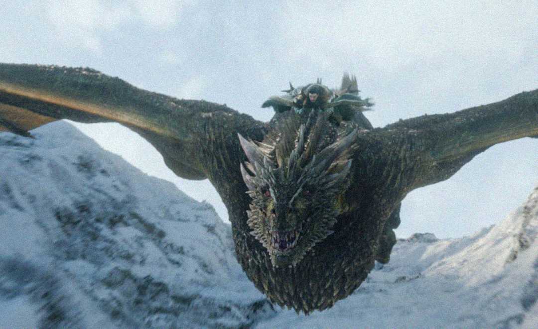 A person rides on the back of a large, flying dragon above snowy mountains, with the dragon’s wings spread wide and its mouth slightly open. The scene appears intense and fantastical.
