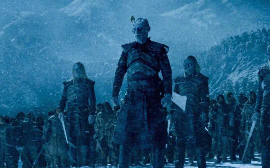 A menacing figure with blue skin and glowing blue eyes stands at the front of an icy army in a snowy, mountainous landscape, flanked by similar figures, under a dark, stormy sky.