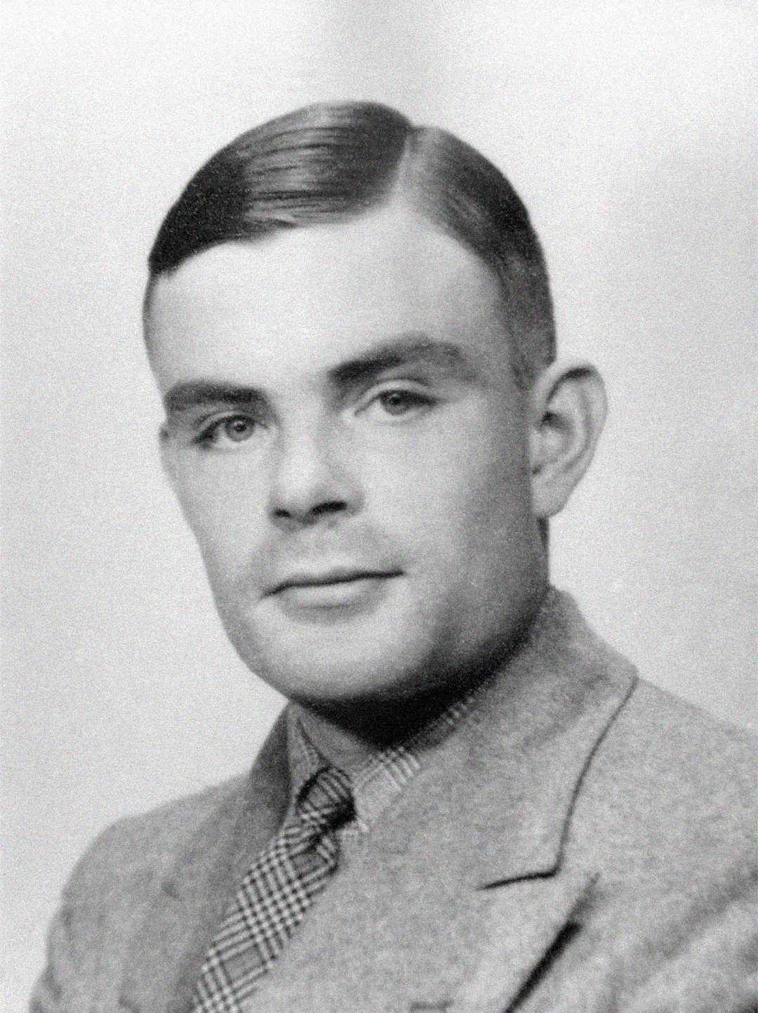 A black and white portrait of a young man with neatly combed dark hair, wearing a suit jacket, dress shirt, and patterned tie, looking slightly to the side with a neutral expression.