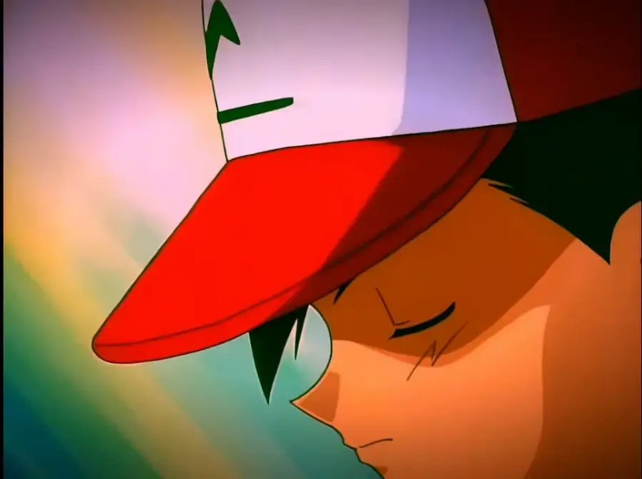 Close-up of an anime character wearing a red and white cap with a green symbol, eyes closed and head slightly bowed, set against a colorful, blurred background.