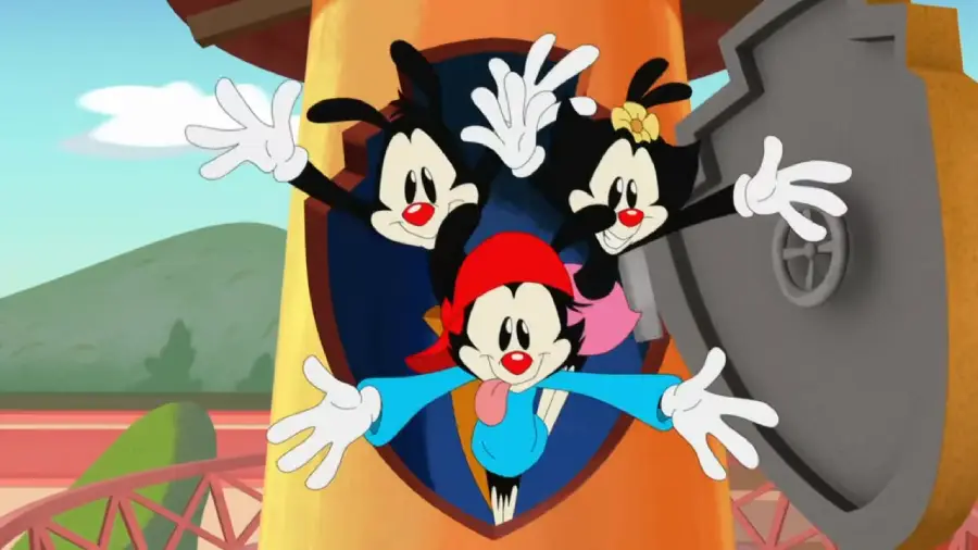 Three cartoon characters with dog-like features and big white gloves energetically jump out of a water tower, smiling with arms outstretched. The background includes hills and a shield-shaped emblem.