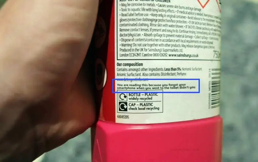 A hand holds a bottle with a label that humorously reads, “You are reading this because you forgot your smartphone when you went to the toilet didn't you.”