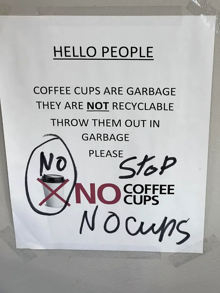 A sign reads: “HELLO PEOPLE. COFFEE CUPS ARE GARBAGE. THEY ARE NOT RECYCLABLE. THROW THEM OUT IN GARBAGE. PLEASE NO COFFEE CUPS.” Handwritten notes say “Stop”, “No cups”, and circle and cross out a cup icon.