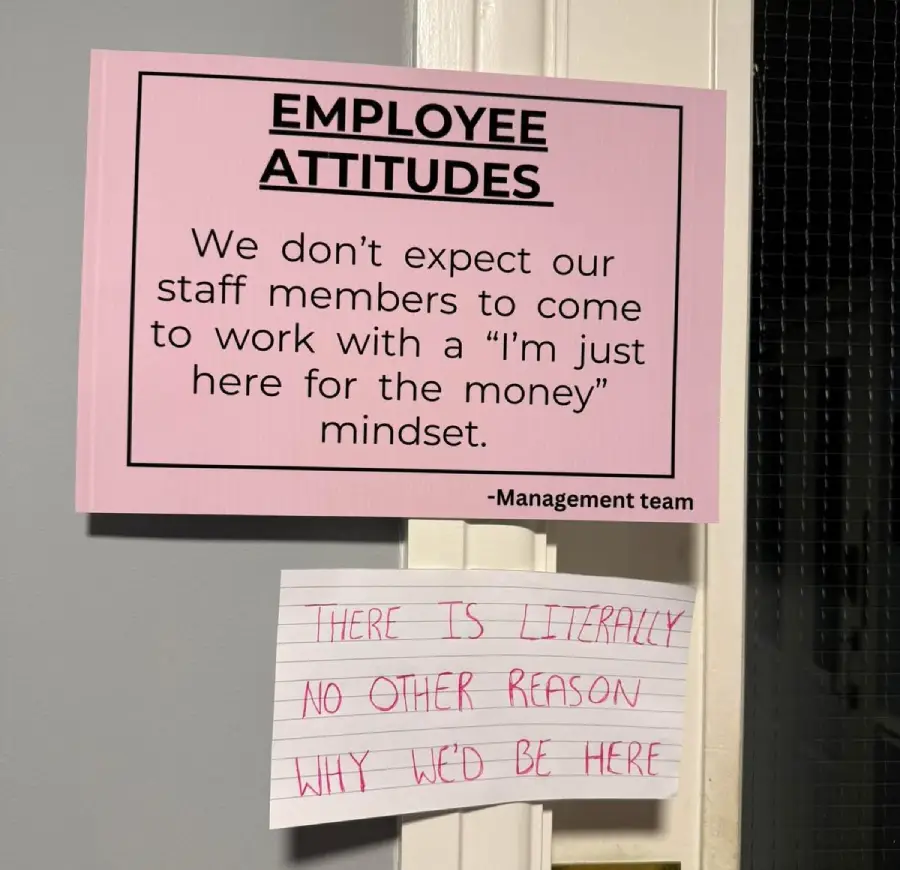 A pink sign reads, "EMPLOYEE ATTITUDES: We don’t expect our staff members to come to work with a 'I’m just here for the money' mindset. -Management team." Below it, a handwritten note says, "There is literally no other reason why we’d be here.