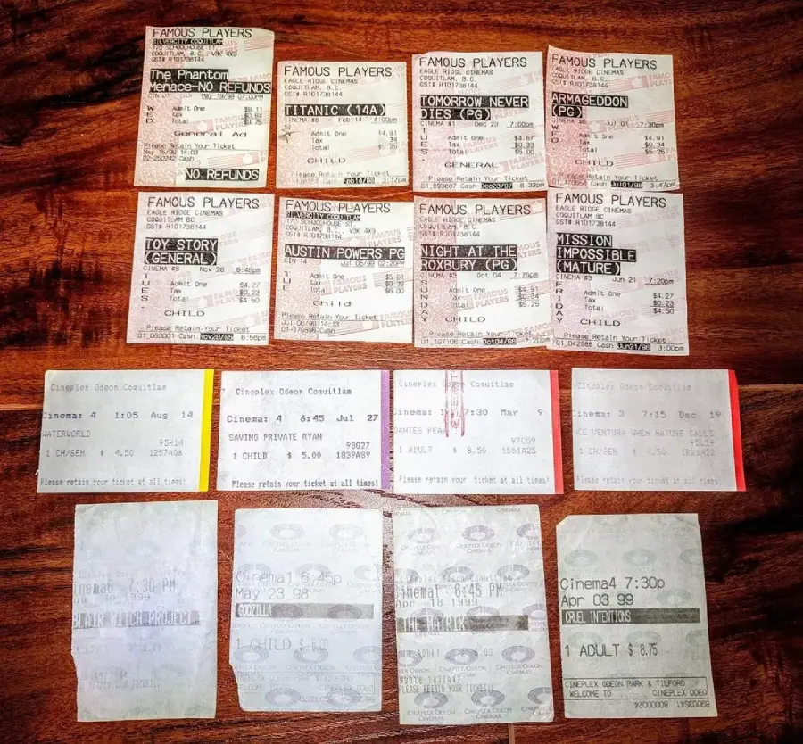 A collection of sixteen old movie ticket stubs, arranged neatly on a wooden surface. The tickets are from various movies and cinemas, showing faded text and different colors and formats.
