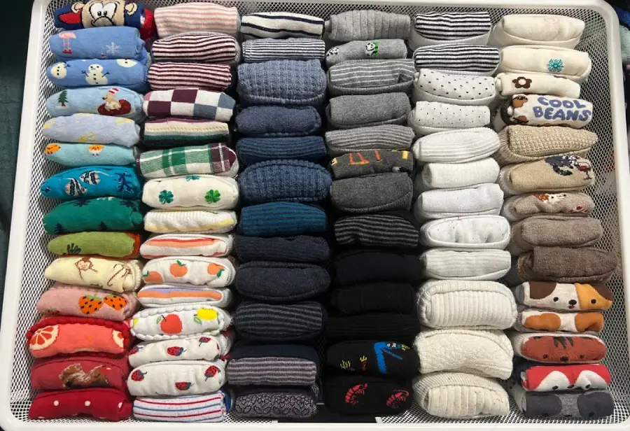 A drawer neatly organized with rows of colorful, folded socks featuring various patterns, including animals, fruits, and stripes, all arranged by color and design.