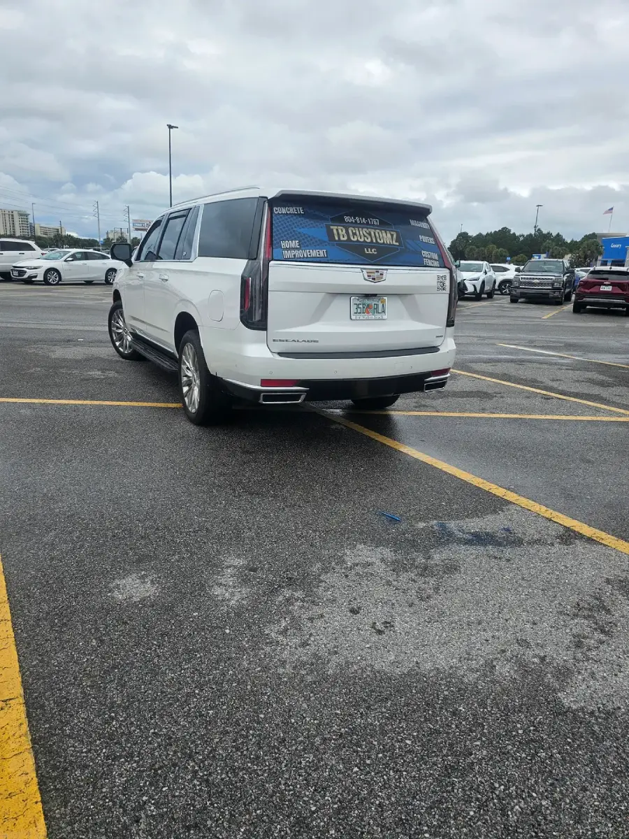 A white SUV is parked diagonally across two parking spaces in a parking lot. The sky is cloudy and several other cars are parked in the background.