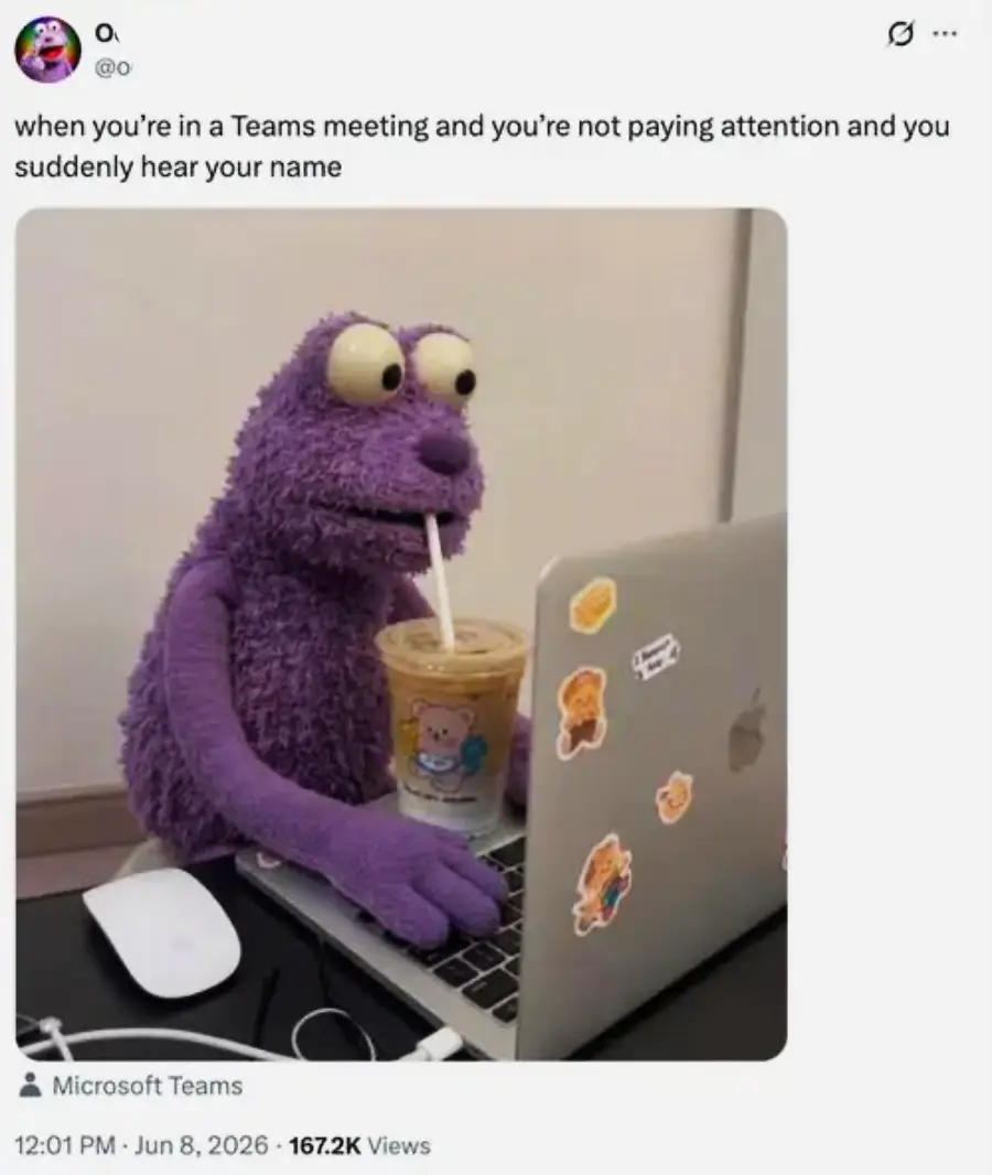 A purple puppet with wide eyes sits at a laptop covered in stickers, holding a cup of iced coffee and looking surprised. The caption jokes about hearing your name in a Teams meeting when not paying attention.