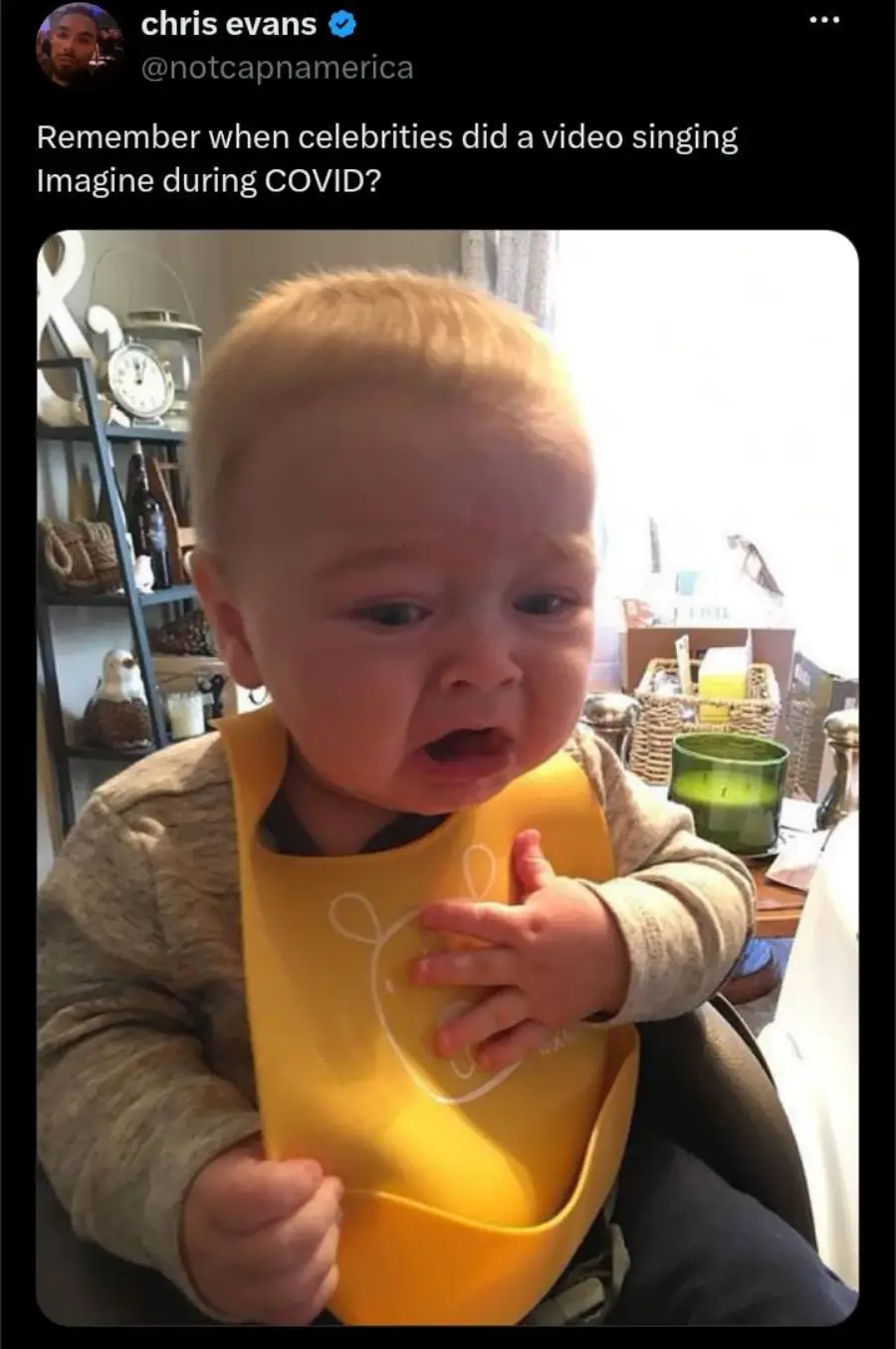 A baby wearing a yellow bib sits in a high chair, looking distressed and on the verge of crying. Above, a tweet jokes about celebrities singing "Imagine" during COVID.