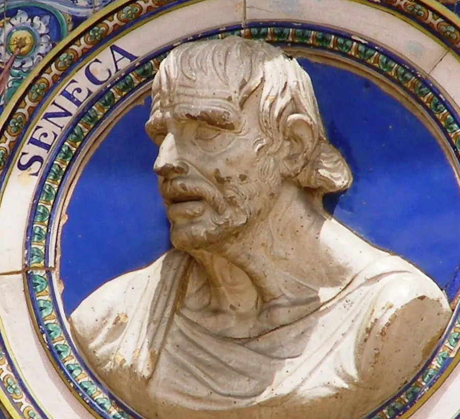 A stone relief bust of the philosopher Seneca is set against a blue circular background with ornate trim. The name "Seneca" is inscribed to the left in uppercase letters.