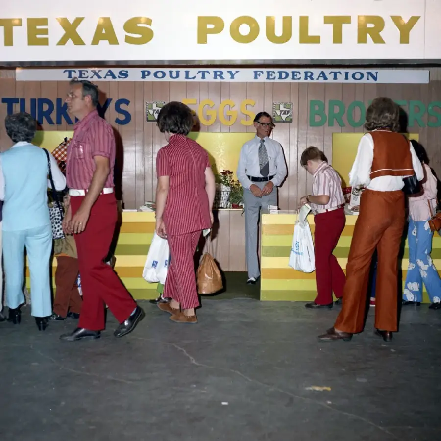 People walk past a "Texas Poultry Federation" booth at an event, with signs for turkeys, eggs, and broilers. The scene features 1970s fashion, including striped shirts and flared pants.
