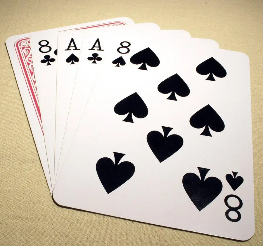 Five playing cards fanned out on a surface, showing the 8 of clubs, 8 of spades, ace of spades, 8 of spades, and 8 of hearts.