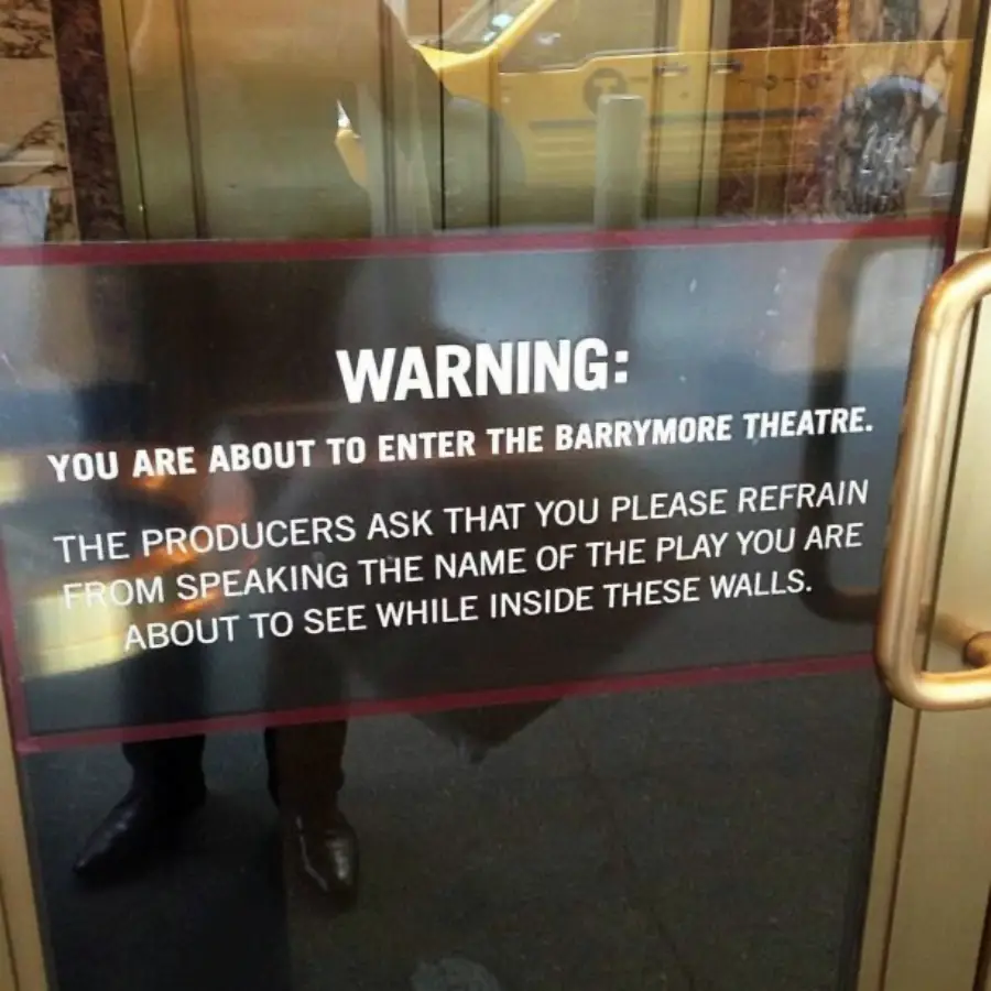 Glass door sign reads: “WARNING: You are about to enter the Barrymore Theatre. The producers ask that you please refrain from speaking the name of the play you are about to see while inside these walls.”