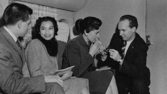 Passengers smoking cigarettes inside a commercial airplane during the 1960s.
