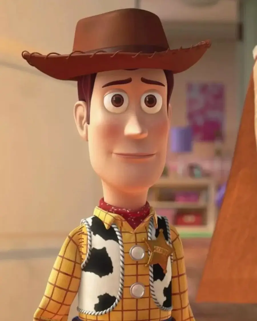 Animated cowboy doll with a brown hat, yellow plaid shirt, red bandana, and cow-print vest, standing indoors. The character appears to be from the Toy Story movie series.