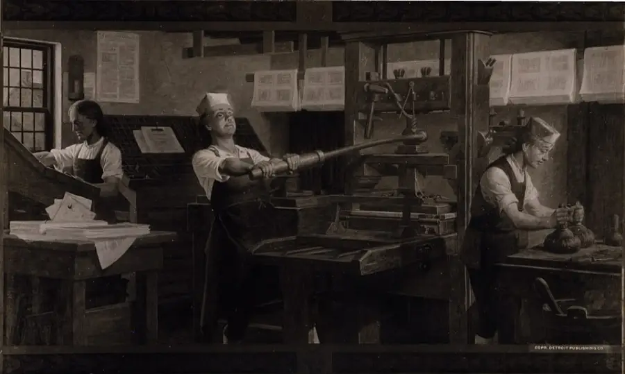 Three people in old-fashioned clothing operate a historic printing press, handling paper and machinery in a dimly lit workshop filled with printed sheets and wooden equipment.