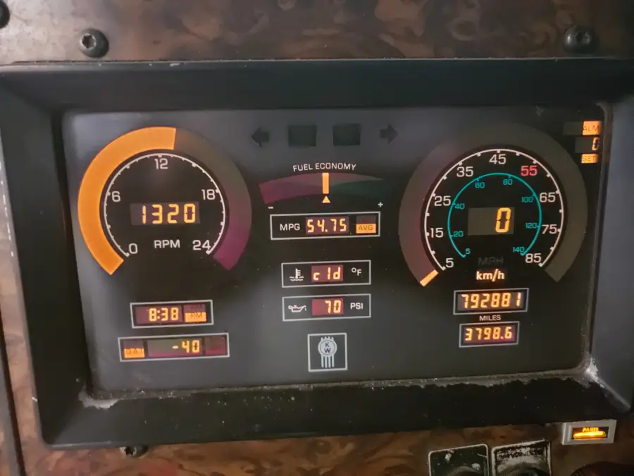 A vehicle dashboard displays 1320 RPM, 0 MPH, 792881 miles, 54.75 MPG fuel economy, -40°C outside, 8:38 time, 70 PSI, and various indicator lights.