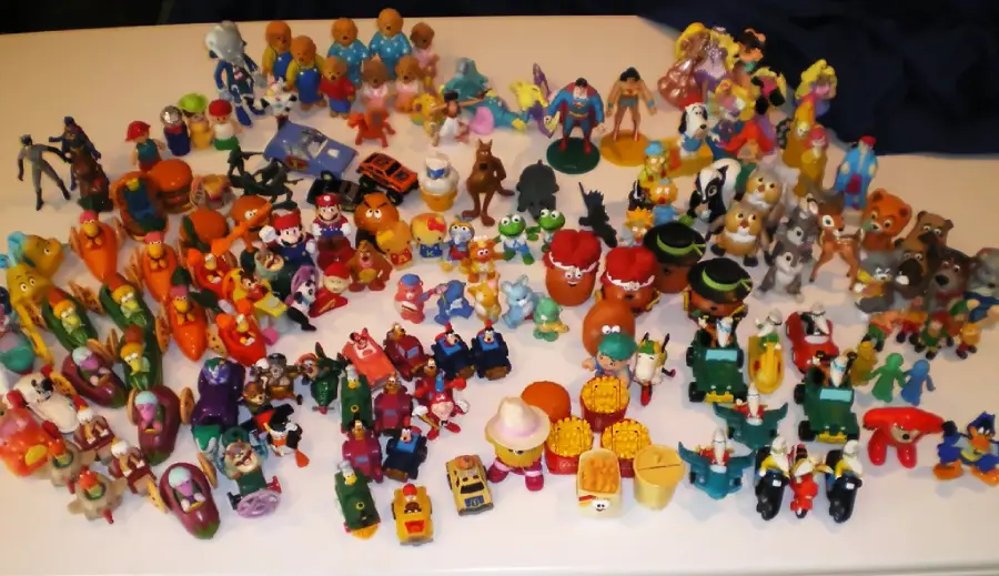 A large collection of colorful fast food toys and figurines, featuring various characters and animals, are spread out on a white surface.